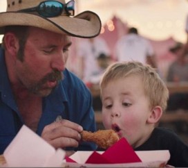 A father gives his son a hot KFC's drum stick chicken and his son blowing off it