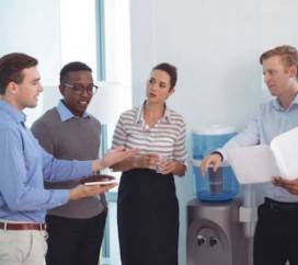 People have a standup meeting infront of water cooler